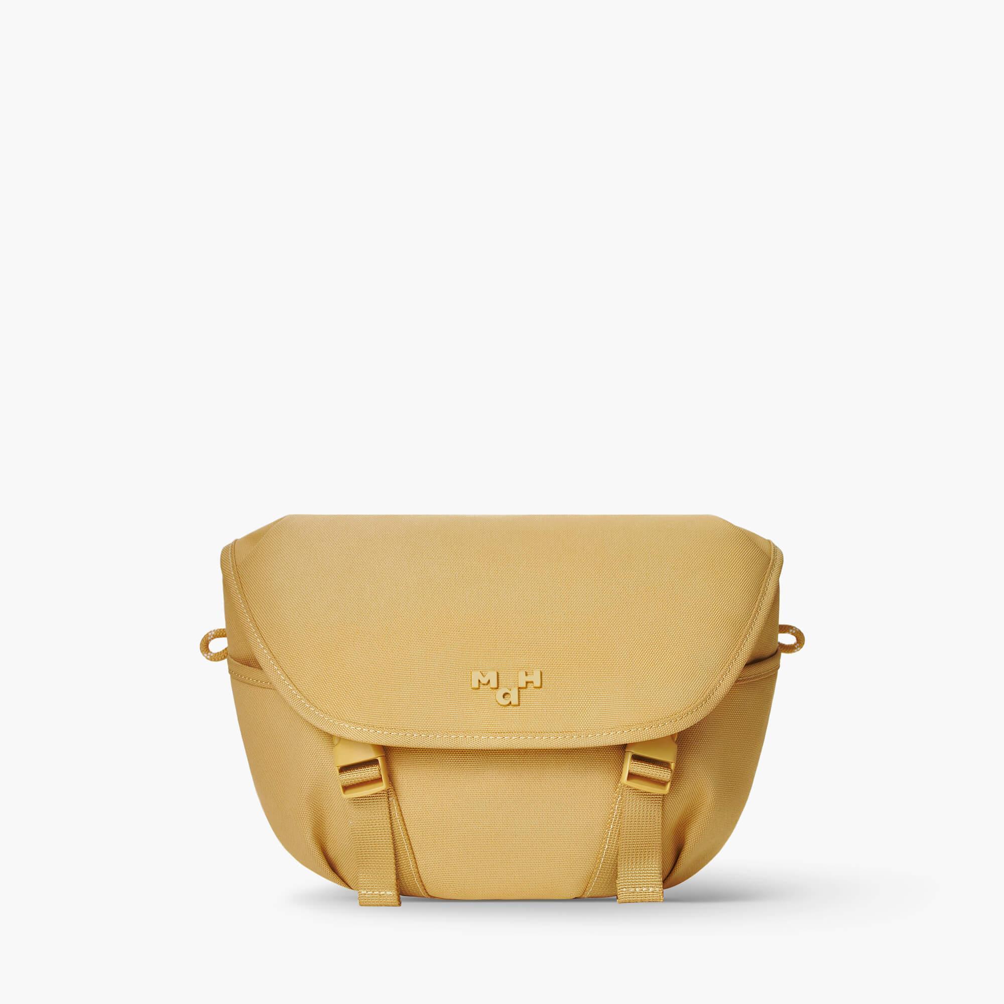 Mustard yellow crossbody bag with flap closure and adjustable straps, ideal for everyday use.