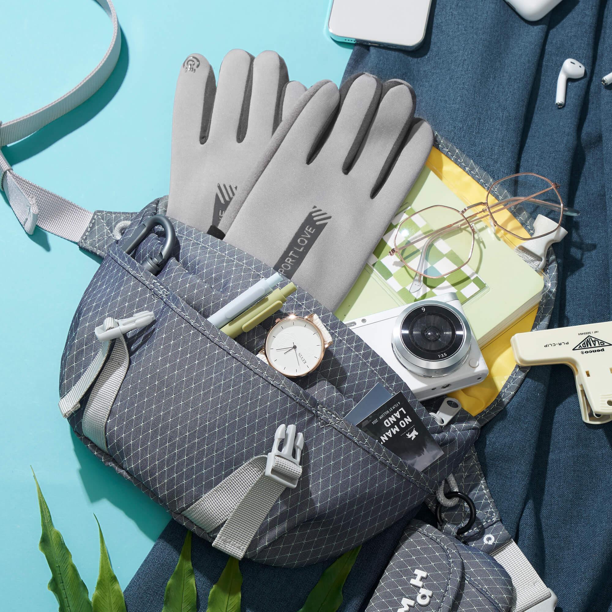 Stylish crossbody bag with gloves, camera, watch, and accessories on blue background
