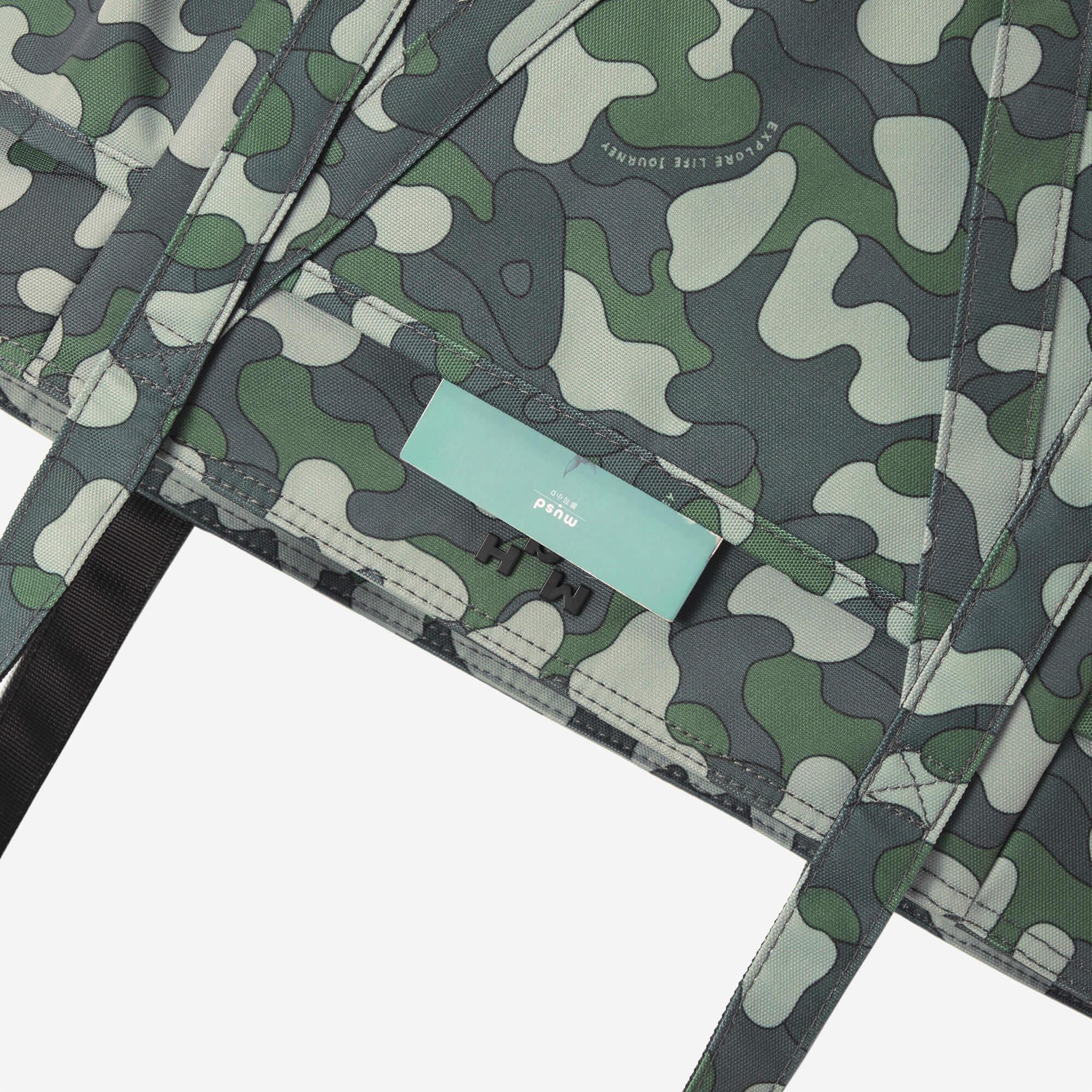Camouflage backpack with green, gray, and white pattern, featuring brand tag and durable stitching
