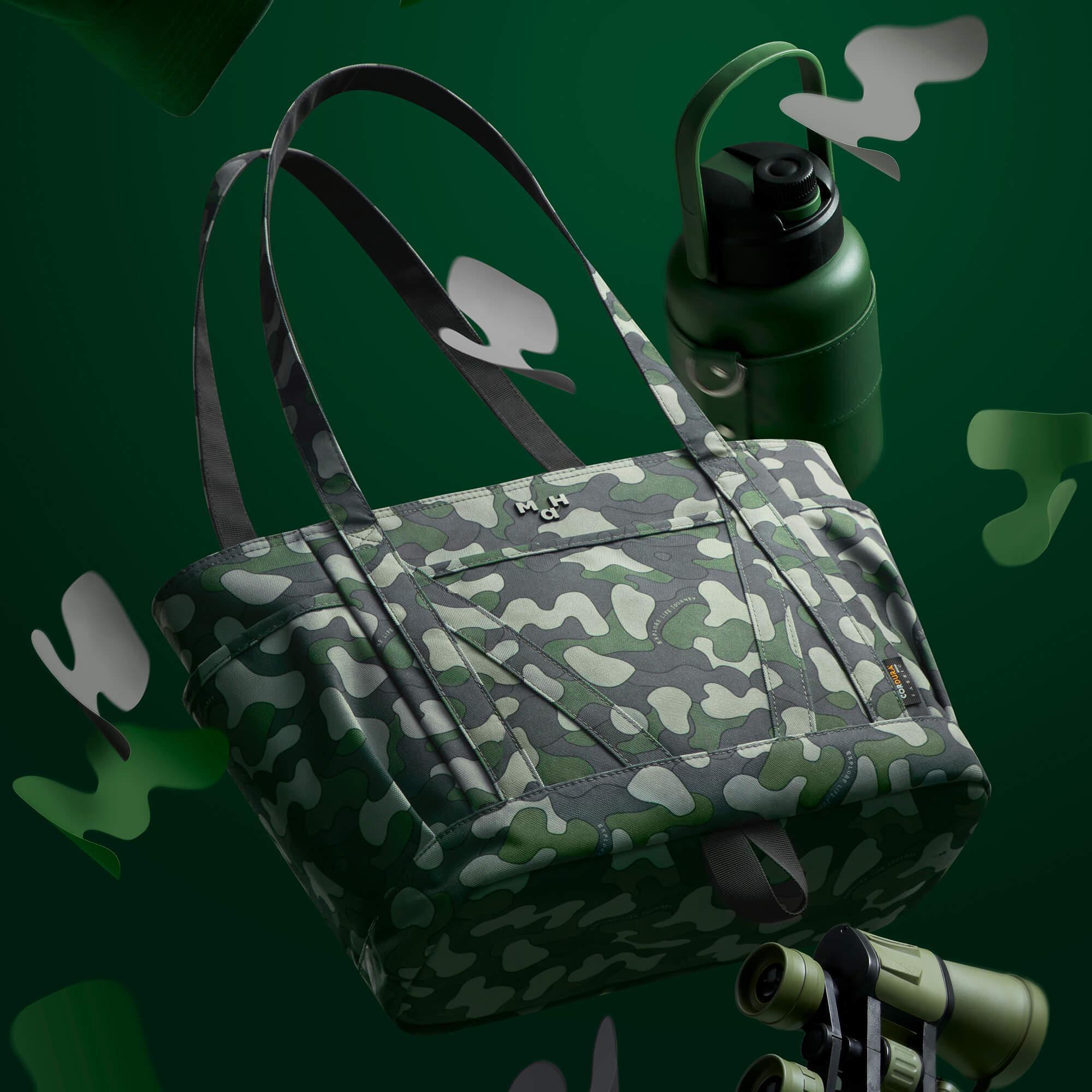 Camouflage tote bag with green water bottle and binoculars on dark green background
